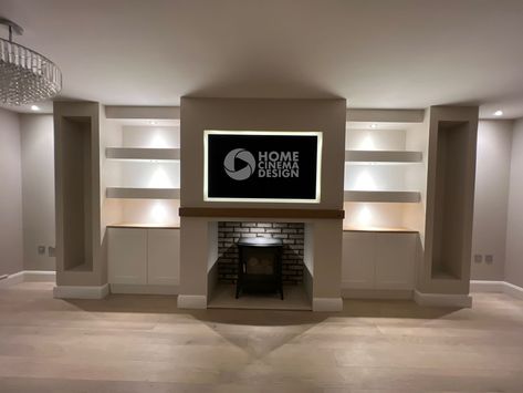 We work with the most stunning electric fires but some, understandably, have a preference for real wood burners. That’s the great thing about Media & Feature walls, they are designed with you, your style and your home at the centre. The real wood burner alcove is backed with brick slip cladding and sits under a solid oak mantel, the floor is created with a high quality stone slab. It houses a 55” Samsung TV is lit with smart lighting and finished with storage cupboards and large log store alco Media Wall With Log Burner, Built In Tv Wall Unit With Wood Burner, Media Wall With Logs, Media Wall With Free Standing Fire, Lounge Tv Storage And Fire, Off Center Woodburner With Tv, Brick Slip, Cupboard Lights, Media Walls