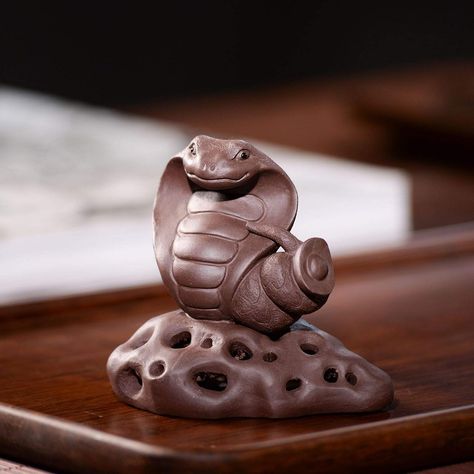 This unique and beautiful tea pet is made of high-quality Yixing purple clay. It is hand-carved in the shape of a king cobra snake, which is a symbol of good luck and prosperity in Chinese culture. The snake is also said to have the power to exorcise evil spirits, making it a popular choice for tea lovers who want to add a touch of luxury and protection to their tea ceremony.

This tea pet is perfect for anyone who appreciates fine craftsmanship and unique objects. Clay Snake, King Cobra Snake, Table Ornaments, Tea Pet, Cobra Snake, Yixing Teapot, King Cobra, Pet Pigs, Clay Figurine