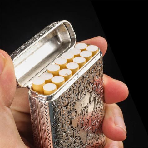 Introducing the Axya Retro Metal Cigarette Case for 14 Smokes, inspired by the iconic Peaky Blinders style. Elevate your smoking experience with this sleek and sophisticated Flick Box Holder. Crafted from high-quality zinc alloy, the Axya Retro Metal Cigarette Case exudes luxury and durability. The Shebil the Gangster model features exquisite hand-carved details, adding a touch of elegance to your smoking accessories collection. With dimensions measuring 996521mm, this cigarette case is designed to hold up to 14 of your favorite cigarettes securely in place. Choose from a selection of timeless colors including Gold, Silver, Black, Bronze, and Red copper to suit your personal style. Experience the convenience and style of the Axya Retro Metal Cigarette Case, perfect for both everyday use an Peaky Blinders Style, The Gangster, Cool Lighters, Cigars And Whiskey, Peaky Blinders, Things To Buy, Little Things, Zinc Alloy, Outfit Accessories