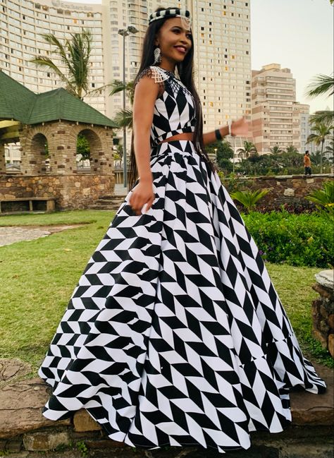 Kitenge 2-piece outfit, accessorised with black and white African beads accessories. Geometric, Black & white, Zulu girl, African young woman. Zulu Dresses, Black And White African Print Dresses, White Kitenge Dress Designs, Black And White Ankara Dresses, Black And White Swati Traditional Attire, Long African Skirt, Black And White Xhosa Traditional Dress, Classy Hairstyles, Girls White Dress