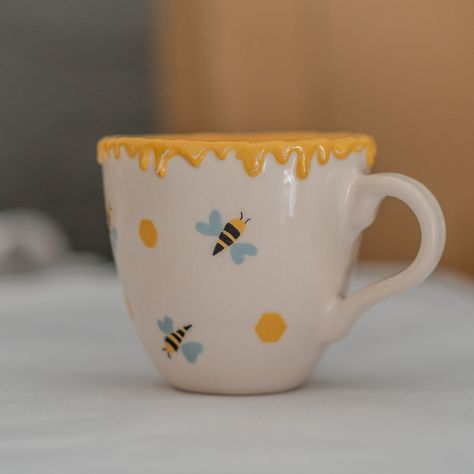 Pottery Mug - Honey and Bee Ceramic Mug: Handmade Coffee Mug, Unique Mug, Nature Lover Gift 🍯🐝 Embrace Nature with Every Sip 🌿🍵 Transform your daily coffee or tea ritual with our stunning Pottery Mug - Honey and Bee Ceramic Mug. Designed for nature enthusiasts, beekeepers, and lovers of all things artisanal, this handmade mug is more than just a beverage holder; it's a celebration of nature's beauty and a testament to exceptional craftsmanship. 🎁 Perfect Gift for Every Occasion Whether it's Bee Ceramic Painting, Glazed Bowls Ceramic Pottery, Coffee Mug Ceramic, Bee Pottery Painting, Mug Inspo Design, Colour Me Mine Ideas Pottery, Simple Mug Designs, Cute Pottery Designs, Cute Clay Mugs