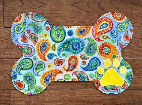 A unique handmade dog feeding placemat is a pretty addition to any pet feeding area. A whimsical paisley fabric design with a signature paw print is a bright addition to your decor. 
Made from three layers of pure cotton to help absorb any spills. Also comes with heavy cotton batting.

Reversible
Vibrant Colors on each side
Size is 18” x 12” which holds 1 or 2 bowls which will accommodate 1 or 2 bowls.

Machine wash - cold
Light-dry or air-dry
Iron on high or low settings Dog Feeding Area, Dog Placemat, Pet Feeding Area, Paisley Fabric, Dog Feeding, Dog Mat, Pet Owner, Handmade Dog, Coordinating Colors