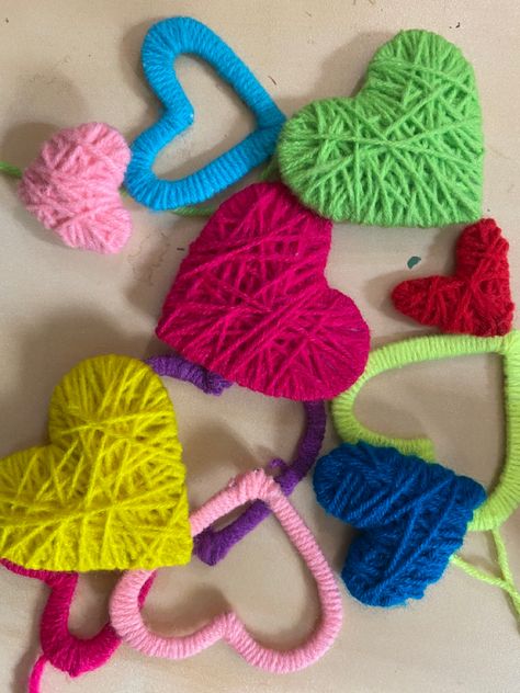 Heart-shaped cut-outs being given a colorful wool wrapping,  to collectively form a Wool Heart Wreath Dangler. Try making one.!! Yarn Wrapped Hearts, Yarn Bouquet, Pom Crafts, Spring Market, Yarn Wall Art, Craft Stalls, Yarn Wall, Diy Fashion Hacks, Best Out Of Waste