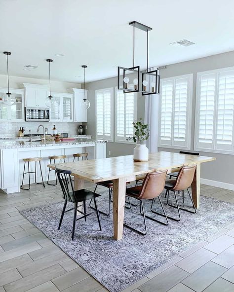 You'll want to show off this light wood dining table lit by a black linear pendant light. The table is set next to a white kitchen island fitted in front of white cabinets. Give your dining set personality by mixing brown leather dining chairs with black spindle end chairs. Brown Leather Dining Chairs, Kitchen Shaker Cabinets, Light Wood Table, Open Kitchen Concept, Light Wood Dining Table, Open Kitchen Layouts, Kitchen Concept, Kitchen Island Tops, Grey Kitchen Island