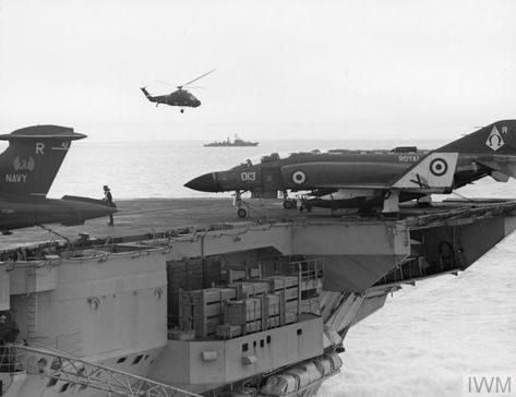 HMS ARK ROYAL at sea during NATO exercises. A Westland Wessex helicopter flies overhead to inspect the approaching Soviet destroyer. Possibly during Exercise Northern Wedding. Northern Wedding, Royal Navy Aircraft Carriers, Hms Ark Royal, Navy Aircraft Carrier, Capital Ship, F 4 Phantom, Windy Weather, Aircraft Carriers, Naval Aviation