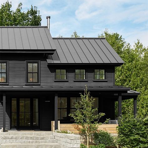 A black-painted house with black trim and front porch, stone steps and greenery. Front Porch Stone Steps, House With Black Trim, Black Siding, Benjamin Moore Exterior Paint, Benjamin Moore Wrought Iron, Front Porch Stone, Benjamin Moore Exterior, Boost Curb Appeal, Black Paint Color