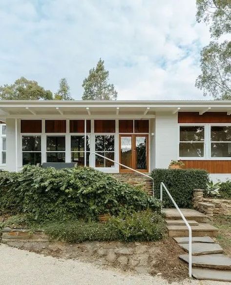 Snugly tucked away in the gorgeous Adelaide Hills, Poppy’s House is a restoration of an authentic 1960s home that stays true to its original charm.  Located in Adelaide’s Mitcham district, the house had barely been touched since it was built in 1967. In fact, the only adjustment that was made is a metal under-deck roof that was installed over the bitumen and strawboard ceiling. Click to see more. 1960s Modern Home Exterior, Light Green Painted Walls, 60s Home Architecture, Two Story Mcm House, Midcentury Mansion, Midcentury Modern House Exterior, Mid Century Architecture 1960s, Mid Century Cabinets, Under Deck Roofing