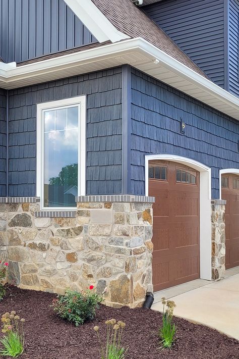 This Craftsman Cottage features our Silver Patina Webwall on the exterior. The earth and shadow tones of this natural stone complement the deep blue siding color of the house leaving a beautiful masterpiece. Blue And Stone House Exterior, Navy Blue And Cream House Exterior, Blue Exterior House Colors With Stone, Blue Home Exterior With Stone, Dark Blue Siding With Wood Accents, Craftsman Blue Exterior, Houses With Blue Siding, Garage Door Colors With Blue House, Blue And Brown Exterior House Colors