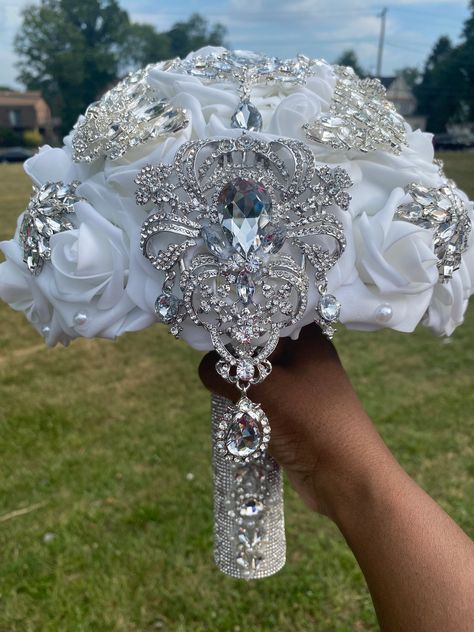 This luxurious bling bouquet is made with real touch artificial roses and silver brooches/gems. Roses are 3 inches wide. Size of bouquet shown is 10 inches wide at the top but can be ordered in a smaller size (8 inches). You may choose any color(s) for your rose bouquet. Please list any additional colors for your roses under "personalization." It will allow you to type a note to me. Please message me if you do not see your color(s). Brooches may vary but are available in silver, gold, or rose go White Silver And Black Wedding, Bouquet Of Flowers White Roses, Silver Wedding Bouquets, White Glitter Roses, Bling Wedding Theme, Quince Bouquet, Pink Rose Wedding Bouquet, Wedding Flowers White, Bling Bouquet