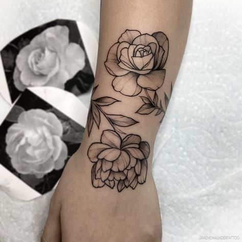 A rose & peony wrapping her wrist. Simplistic black and grey tattoo. (by Graeme Maunder)  #tattoo #tattoos #vancouvertattoo #flowertattoo #rosetattoo #peonytattoo #tattooartist #peonytattoo #floraltattoo #artwork #floralartwork #blackwork #blackandgrey #vancouvertattooartist Tatt00 Ideas, Pink Peony Tattoo, Hairstylist Tattoos, Wrap Around Wrist Tattoos, Inspiring Quote Tattoos, Floral Tattoos, About Rose, Peonies Tattoo, Stylist Tattoos