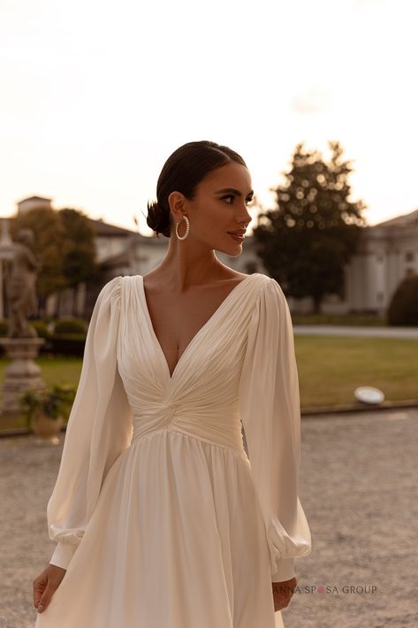 Buy wedding dress Camellia from the producer - Anna Sposa Group Long Sleeve Drape Dress, Pleated Maxi Dress With Sleeves, Grecian Wedding Dress With Sleeves, Long Sleeved V Neck Wedding Dress, Late Fall Wedding Dress, Long Sleeve Empire Waist Wedding Dress, Boho Classic Wedding Dress, Long Sleeve Wedding Dress Mid Size, Empire Waist Wedding Dress With Sleeves