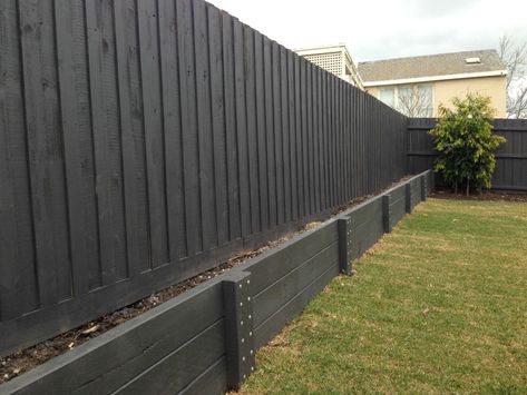 Retaining Wall Side Of House, Concrete Retaining Wall Makeover, Retaining Wall Under Fence, Black Wood Retaining Wall, Modern Farmhouse Retaining Wall, Black Retaining Wall Garden, Fence Retaining Wall, Painted Timber Retaining Wall, Black Retaining Wall