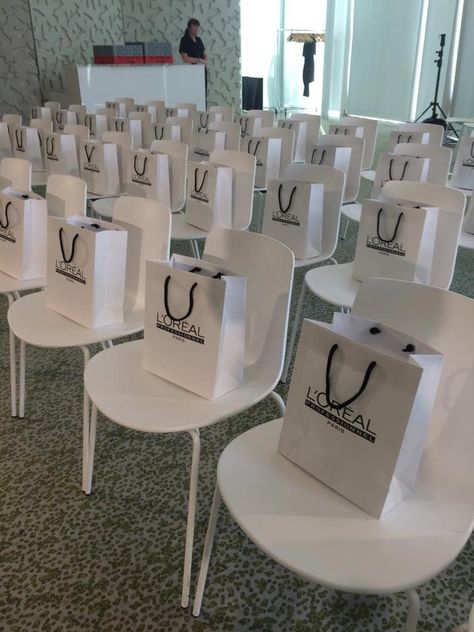 Simple and Minimalistic corporate event chair arrangement with souvenir bags Fashion Show Gift Bags Ideas, Grand Opening Goodie Bags, Event Goodie Bags, Beauty Masterclass Event, Makeup Event Ideas, Work Event Decor, Makeup Launch Event, Conference Decorations Events Ideas, Corporate Goodie Bags