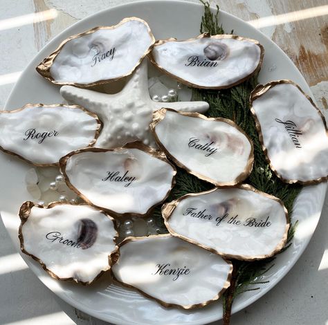 Welcome to our exclusive collection of personalized oyster shell place cards, designed to add a touch of elegance and luxury to your special day. Each place card is a unique masterpiece, crafted to be a stunning keepsake for your guests. ✨ Why You'll Love These Oyster Shell Place Cards: Customizable Elegance: Each Oyster Shell will have a glossy finish and is adorned with a gold paint trim, adding a touch of sophistication. Unique Keepsakes: These place cards double as memorable wedding favors. Ocean Wedding Inspiration, Oyster Shell Wedding Place Cards, Oyster Place Cards, Oyster Shell Wedding Favors, Oyster Wedding Favors, Coastal Classic Wedding, Oyster Place Cards Weddings, Unique Wedding Name Place Cards, Oyster Name Cards