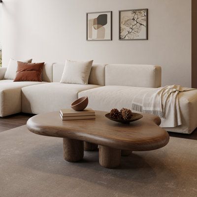 This coffee table brings sleek style and warm wood to center stage. It's made from solid and engineered wood, with natural wood grain color variation giving it an organic, lightly weathered look. This table features a smooth, hourglass-style silhouette - rounding out your space while offering visual dimension. Place it in front of your loveseat or sofa, and use it to rest books, beverages, and display items. Then, sit back and watch as it ties your space together. | Orren Ellis Olvia 48.4inch Wa Warm Minimalist Furniture, Asymetrical Coffee Table, Small Living Room Mid Century, Circle Ottoman Coffee Table, Organic Modern Coffee Tables, Irregular Shaped Coffee Table, Coffee Table With L Shaped Couch, Curvy Coffee Table, Asymmetrical Coffee Table