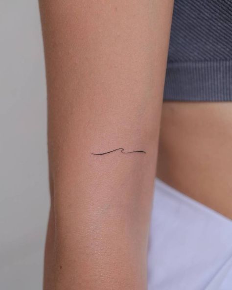 Minimalistic style wave tattoo placed on the upper arm. Mini Tattoos Wave, Body Of Water Tattoo, Minimalist Wave Tattoo Simple, Cool Wave Tattoos, Wavey Line Tattoo, Waves Fine Line Tattoo, One Line Wave Tattoo, Dainty Beach Tattoos For Women, Wave Tattoo On Arm