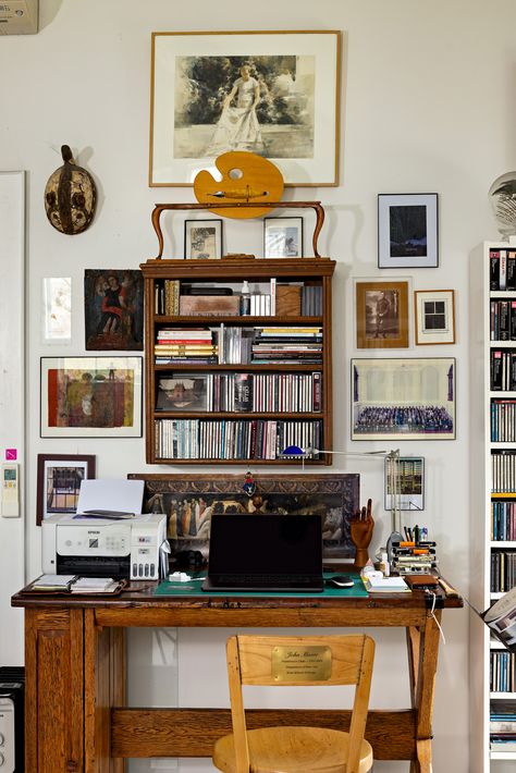 Step inside this Belfast studio to find an artist's eclectic work from home office. A vintage paint palette and fountain pen decorate the space above the desk. Below, a small bookshelf is filled to the brim with CDs. Assorted framed photos and drawings cover the walls, each with a different artistic style to create a unique gallery wall. The desk itself is made of rich wood, it is paired with a custom-engraved chair. Wall Desk With Shelves, Desk With Shelf Above, Bookshelf Above Desk, Vintage Eclectic Home Decor Ideas, Graphic Designer Desk Setup, Vintage Office Decor Ideas, Vintage Desk Aesthetic, Above Desk Decor, Maine Interiors