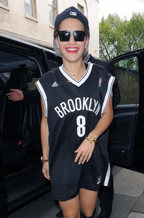 It's all about the accessories here. Rita Ora softens her sporty look with gold jewelry and her signature red lip.    - ELLE.com Nba Jersey Outfit, Sports Jersey Outfit, Basketball Game Outfit Women, Basketball Jersey Outfit, Summer Dump, Basketball Game Outfit, Jersey Fashion, Jersey Outfit, Basketball Jerseys