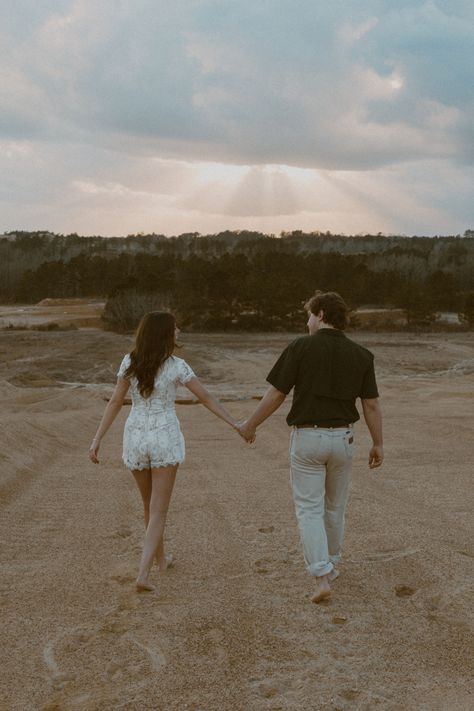 A vintage edit of a couple holding hands and walking in sand. #couplesphotoshoot #couplesphotography #engagementphotos #engagementphotoshoot #documentaryphoto #vintagephotography #sunsetphotography Couple Walking Photo, People Holding Hands Reference, Couples Holding Hands Walking, Holding Hands From Behind, Couple Walking Holding Hands, Rachel Tattoo, Cottagecore Couple, Two People Holding Hands, Parallel Play