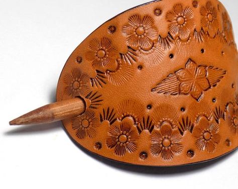 Oval shaped tooled leather Boho style floral hair slide with double pointed bamboo hair stick. This barrette is medium brown in color with matching bamboo hair stick, and depicts a Boho style centered flower design with floral border. Has black edges & back side. This hair pin is a great decorative addition to any ponytail or updo, and is totally hand tooled from durable, thick cowhide leather. Hair slide measures approximately 3.25"x2.25". Initial measurement of hair slide is taken while cu Leather Hair Barrette With Stick Diy, Leather Hair Cuff, Tooled Leather Hair Clips, Tooled Hair Clip, Wooden Hair Barrette, Tooled Leather Hair Barrette, Leather Hair Accessories, Leather Working Tools, Leather Jewelry Making