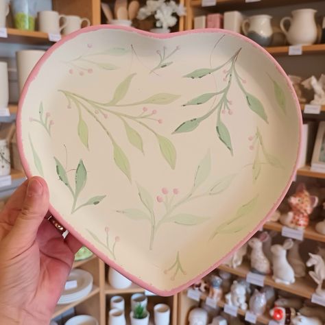 Green leaves and red berries on a heart plate, before firing, pottery painting Pottery Painting Ideas Leaves, Pottery Painting Heart Plate, Valentine Pottery Painting Ideas, Heart Pottery Painting Ideas, Heart Bowl Pottery Painting, Pottery Painting Hearts, Heart Plate Pottery Painting, Pottery Painting Green, Green Pottery Painting