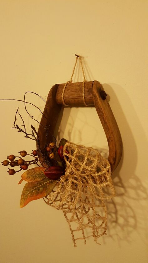 Western stirrup with fall decor. Designed by Carol. Old Saddle Decor Ideas, Decorating With Old Horse Bits, Horse Stirrup Crafts, Western Decorating Ideas, Old Stirrup Ideas, Wood Stirrup Decor, Western Christmas Decorations, Horse Nails, Horse Wreath