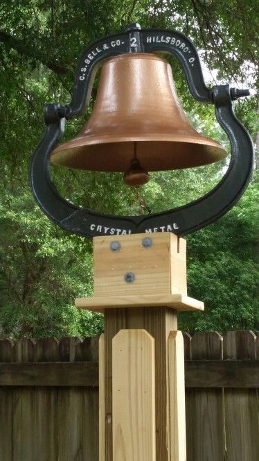 Cast Iron Bell Ideas, Cast Iron Bell On Post, Farm Bell On Post, Dinner Bell Ideas, Dinner Bell Post, Bell Stand, Rustic Yard Decor, Cast Iron Bell, Bell Gardens