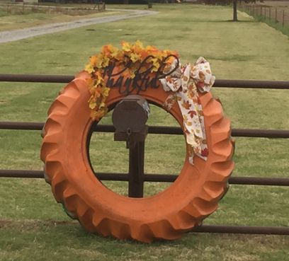 Tractor tire wreath Tractor Tire Pumpkin, Small Tire Projects, Pumpkin Tires, Tire Wreath Christmas, Tire Pumpkins, Tractor Tire Wreath, Tractor Tire Ideas, Hay Bale Decorating Ideas, Tire Decor