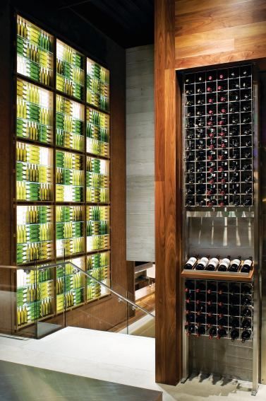 Empty wine bottles backlit by LED fixtures form a sculptural feature wall at the top of the main staircase that leads to the tasting bars. The empty bottles are complemented by full ones in the nearby retail display, which was designed and fabricated by Eclipse Designs.    Rien van Rijthoven Wine Bottle Fence, Wine Bottle Wall, Architect Magazine, Empty Wine Bottles, Bottle Ideas, Bottle Display, Bottle Wall, Wine Wall, Wine Display