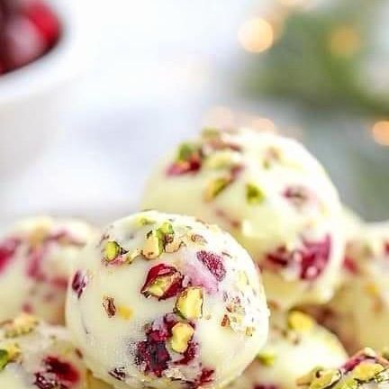 Alla Driksne | Online Cake Academy on Instagram: "Cranberry Pistachio White Chocolate Truffles 

Ingredients:
1 cup white chocolate chips or finely chopped white chocolate
1/4 cup heavy cream
1/4 cup dried cranberries, chopped
1/4 cup pistachios, chopped
1/2 teaspoon vanilla extract
Extra chopped pistachios and cranberries for rolling (optional)

Instructions:

Place the white chocolate in a heatproof bowl.
In a small saucepan, heat the heavy cream over medium heat until it just begins to simmer. Do not let it boil.
Pour the hot cream over the white chocolate and let it sit for 2-3 minutes to melt the chocolate. Stir until smooth.

Add Flavors:
Stir in the vanilla extract, chopped cranberries, and chopped pistachios until evenly distributed.

Chill the Mixture:
Cover the bowl with plastic Cooking Cranberries, Pistachio White Chocolate, Christmas Cranberry, Raw Treats, Facebook Recipes, White Chocolate Truffles, Cranberry Pistachio, Candy Truffles, White Chocolate Cranberry