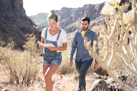 Woman holds a map and walks on a mountain path in the desert with a man walking behind her Mountain Path, In The Desert, The Desert, Walk On, Grand Canyon, A Man, Hold On, Ruffle Blouse, Walking