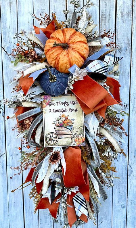 This cozy fall swag would look great on your front door with your fall decor.  This wreath is rich in colors of orange, blue and cream and lots of textures of wheat and raffia.  This swag has a large orange pumpkin with lots of texture an a smaller. lue velvet pumpkin.    Orange, Taupe and cream velvet is used throughout the swag.  This wreath measures 46" high x 26" wide x 10" deep. Fall Swags For Front Door Diy, Fall Swags For Front Door, Blue Fall Wreath, Wreath With Sign, Wreath With Pumpkins, Fall Decor Wreaths, Fall Fireplace, Fall Swags, Bowling Green Ky