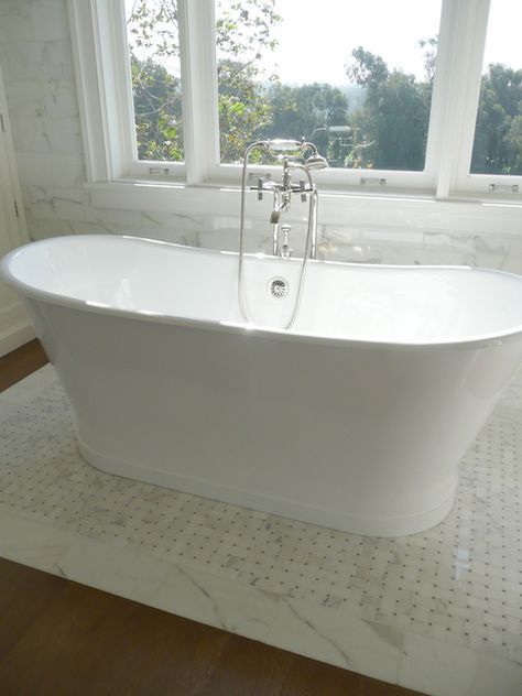 Elegant bathroom with freestanding bathtub paired with a floor mount tub filler in front of window framed by marble subway tile over hardwood floors accented with a marble basketweave tiled rug which anchors the tub Manhattan House, Wood Floor Bathroom, Rental Bathroom, Bathtub Tile, Bathroom Accessories Luxury, Master Bathrooms, Renovation Inspiration, Tub Ideas, Living Vintage