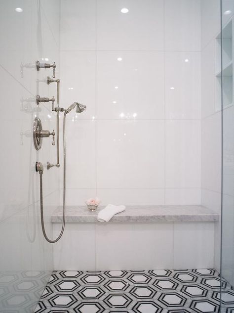 Walk-in shower features white, gray, and black hexagon floor tiles leading to a honed marble shower bench fixed against glossy white stacked shower surround tiles. Marble Shower Bench, Black Hexagon Floor, Hexagon Floor Tiles, White Shower Tile, Hexagon Floor, New Ravenna, Glass Shower Doors Frameless, Marble Showers, Honed Marble