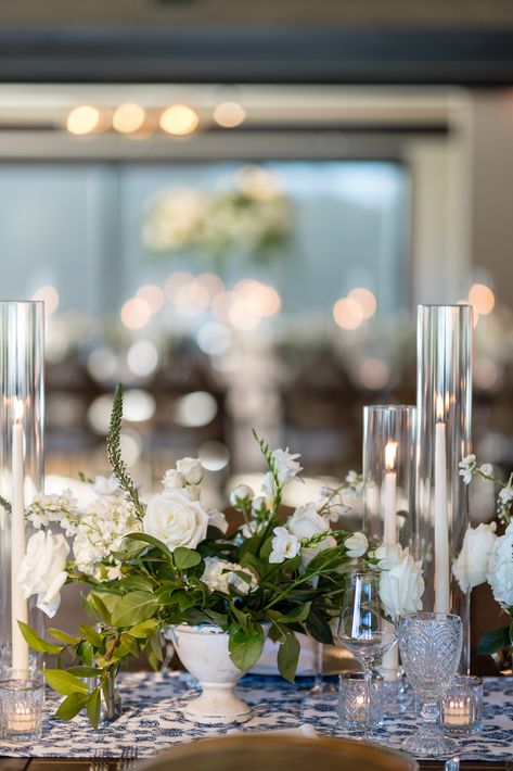 White rose, white hydrangea, white freeisa, white delphinium, lysimachia, greenery - white footed bowl compote farm table centerpiece - white taper candles, glass candlesticks Blue Accent Wedding, Wedding Farm Table, Farm Table Centerpiece, White Delphinium, White Taper Candles, Hydrangea White, Wedding Farm, Glass Votives, Blue Accent