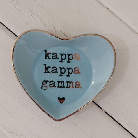 Ceramic ring dish is the definition of chic with it's high gloss finish and sorority name, heart and edge in gold. Great for rings, jewelry, keys or trinkets. Perfect for home or office! Size: 4 3/8" x 3 5/8 Available in Delta Delta Delta, Phi Mu, Alpha Chi Omega, Delta Gamma, Chi Omega, Delta Zeta, Kappa Alpha Theta, Kappa Kappa Gamma, Pi Beta Phi, Zeta Tau Alpha. Sorority Accessories, Kappa Delta Gifts, Kappa Delta Crafts, Chi Omega Game Day Buttons, Alpha Gamma Delta Merch, Kappa Delta Game Day Buttons, Sorority Names, Ceramic Ring Dish, Kappa Kappa Gamma