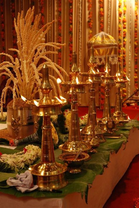 Nilavilakku - A lighted lamp stands for auspiciousness and is considered a welcoming sign. In a traditional Malayali wedding these play an integral role. You line them up in odd numbers (usually 3 or 5) in front of the wedding madapam (alter) and light them with oil and wicks. Kerala Decor, Malayalee Wedding, Hindu Wedding Decorations, Indian Theme, Diwali Decorations At Home, Desi Wedding Decor, Wedding Mandap, Wedding Stage Decorations, Indian Decor