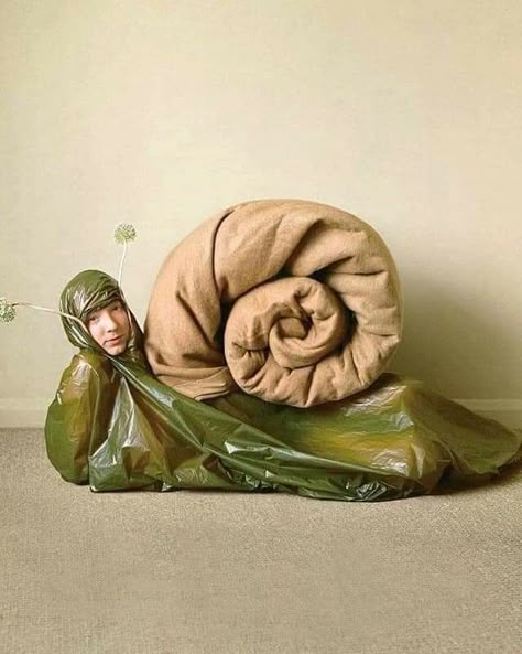 A man dressed as a snail smirks peacefully at the screen. His outfit is made of green plastic garbage bags for his body, and a folded ochre duvet for the shell. An antenna tiara brings more absurdism. There is nothing in the scenery, besides a cream-colored wall and a lightly darker carpet. Art Bizarre, Fantasias Halloween, Halloween Inspo, Halloween Costume Ideas, Fancy Dress, Halloween Ideas, Art Direction, Costume Ideas, The Floor