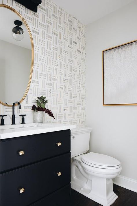 Marble and brass tiles create a stunning bathroom accent wall featuring a gold mirror above a black washstand finished with a matte black faucet. Powder Room Wallpaper Black Vanity, Caribbean Theme Bathroom, Black Floor Powder Room, Half Bath With Wallpaper Accent Wall, Modern Bathroom With Wallpaper, Half Bath Wallpaper Accent Wall, Powder Room Accent Wall, Small Powder Room Wallpaper, Powder Room Tile