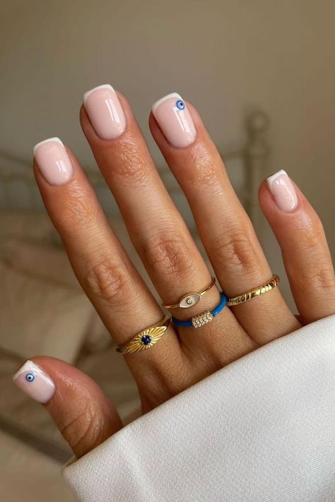 Soft pink nails present an understated elegance, each adorned with a single, miniature evil eye charm at the base for a touch of mystique. The glossy finish adds a subtle sheen that complements the minimalist design, creating a serene yet enchanting look.👁✨  // Photo Credit: Instagram @aniahaie Evil Eye Nails Design, Evil Eye Nails, Nagel Tips, Easy Nails, Summery Nails, Skin Nails, Cute Gel Nails, Short Nail Designs, Nailed It