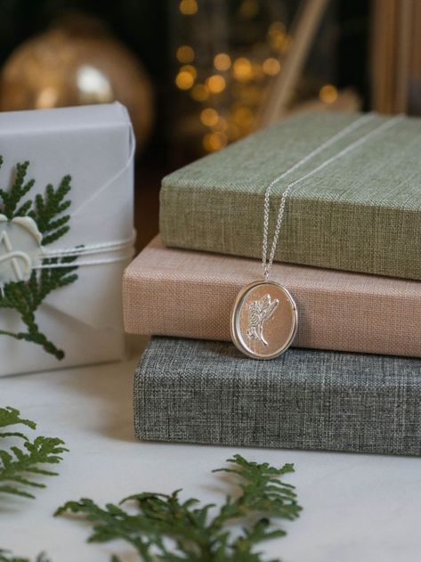 Photo of a silver necklace with a birch design on it. The necklace is laid out on some books with twinkle lights in the background and cedar. Christmas Jewelry Packaging, Winter Jewelry Photography, Christmas Jewellery Photoshoot, Winter Jewelry Photoshoot, Christmas Jewellery Photography, Christmas Jewelry Photography, Winter Accessories Jewelry, Jewellery Shots, Earring Photography