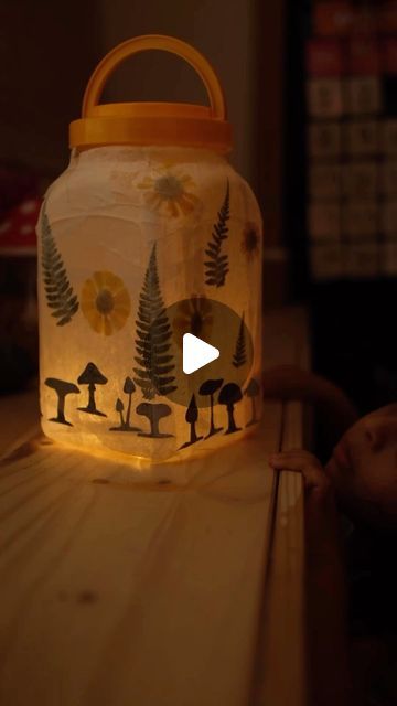 Sibia Torres Padilla | DIYs on Instagram: "I made one of these little lanterns months ago for the kids to go camping or on walks and it worked out perfectly.

two months ago we visited my mom and she gave the kids another container of jellies, so I knew it was time to make a second lantern

Because they are made with upcycled plastic containers, they are really lightweight and easy for the kids to bump around and walk with.
 
first, I cleaned the container and removed the stickers. If there is a little bit of sticky residue left, that’s OK because we’re going to cover it anyway. 

Then I added some mod podge and one layer of white tissue paper 

after that, I added, these mushroom silhouettes, as well as some dried florals also using mod podge 

When that was dry, I added the last layer of Plastic Containers, Mod Podge, Me Clean, Diy Lamp, Go Camping, Tissue Paper, Plastic Bottles, Cute Crafts, Craft Tutorials