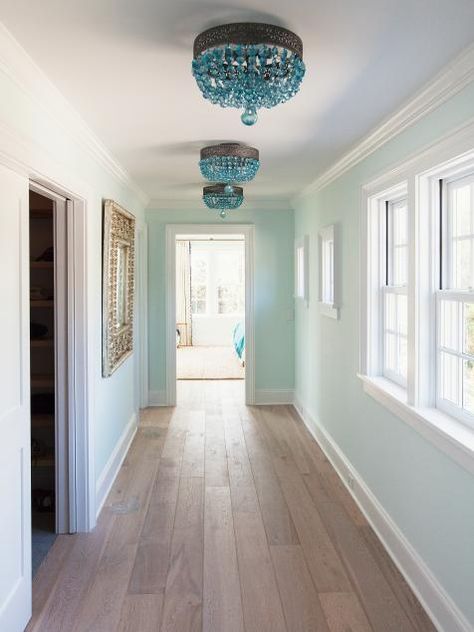 A trio of blue crystal light fixtures line a hallway leading to the master bedroom. Teal Hallway, Novogratz Design, Sunset House, Island Beach House, Light Wood Floors, Have Inspiration, Beach House Design, Small Hallways, Hallway Lighting