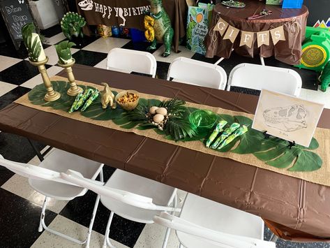 Dinosaur inspired table decorations. Jurassic Park Party Table Decorations, Jurassic World Birthday Centerpieces, Jurassic Centerpieces, Jurassic Park Party Centerpieces, Jurrasic World Birthday Party Ideas Diy, Jurassic World Birthday Party Games, Jurassic Park Centerpieces Ideas, Dinosaur Birthday Centerpiece Ideas, Jurassic World Centerpieces