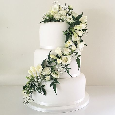 White wedding cake with trailing fresh white flowers and greenery Wedding Cake Greenery, 4 Tier Wedding Cake, Green Wedding Cake, Cake Decorating With Fondant, Fondant Wedding Cakes, Icing Flowers, Wedding Cake Roses, Fresh Flower Cake, Dream Wedding Cake