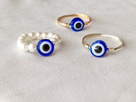 (items are shipped between 1-2 days) Evil Eye Ring, Wire Wrapped Ring, Wire Wrapped Evil Eye Ring *A gold or silver wire wrapped Evil eye ring  *elastic pearl evil eye ring These Evil Eye Rings are made out of a plastic evil eye silver or gold wire. The wire size is a 22 gauge wire. The second option Evil Eye ring is made with an elastic string and 4mm Pearl beads. The Evil Eye Bead comes in both a Pink Evil Eye Bead and Blue Evil Eye Bread. These dainty rings are perfect for layering or wearing Evil Eye Rings, Eye Ring Silver, Evil Eye Ring Silver, Evil Eye Ring Gold, Eye Rings, Hippie Rings, Heart Anklet, Ring Wire, Sterling Silver Cross Necklace