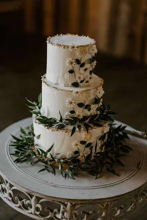 White three tier rustic wedding cake with iced flowers and green foliage Forest Fairy Wedding Cake, Wedding Cakes Green And White, Camp Wedding Cake, Wedding Cake Three Tier Flowers, Modern Rustic Wedding Cake, Elven Wedding Cake, Light Green Wedding Cake, Wedding Cakes Forest Theme, Dark Green And White Wedding Cake