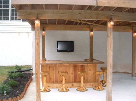 Royersford, Pa.  8x5 custom red cedar tiki bar, I custom fit this tiki bar under his deck and incorporated the support poles from his deck into the bar. There is electric, cable tv, 3 outlets, fridge, rope lighting, 6 bar stools, solid cherry bar top, lower bar top and cabinets. Full photo album can be seen here on facebook - https://www.facebook.com/tikikev/photos_albums . For more info go to www.tikikev.com or contact me directly at 800-792-8454 , or email to tikikev@tikikev.com Outdoor Deck Decorating, Under Deck, Outdoor String Lights Patio, Deck Bar, Porch Bar, Play Area Backyard, Cedar Deck, Indoor Lights, Tiki Bars