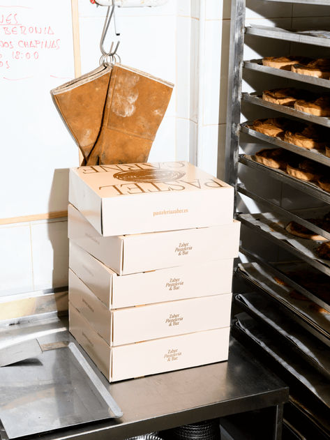 Angled flash photography of the interior of the bakery, showing several boxes or the packaging of the meat pies stacked in the centre, next to the shelf with the trays with the pies. Traditional Bakery, A Typography, Small Business Packaging, Meat Pie, Bakery Shop, The Chef, Typography Fonts, Brand Design, Packaging Design