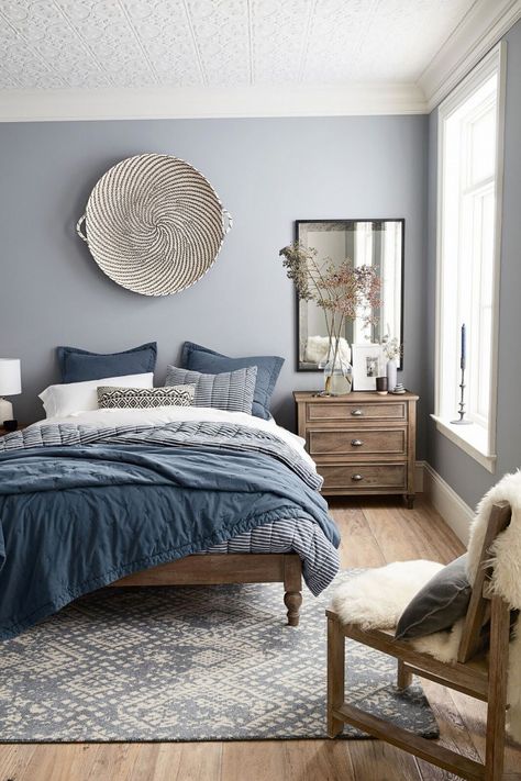 Modern bedroom design featuring a blue, gray, white and wood tone color scheme, a large woven basket as wall decor over the bed, layers of blue, gray, and white bedding, a large antiqued mirror over a wood bedside table, and a sheepskin throw on a wood chair - Home Decor & Decorating Ideas - mydomaine.com Design Ložnic, White Basket, Diy Wand, Grey Bedroom, Bilik Tidur, Hus Inspiration, Spare Bedroom, Bedroom Paint, Blue Bedroom